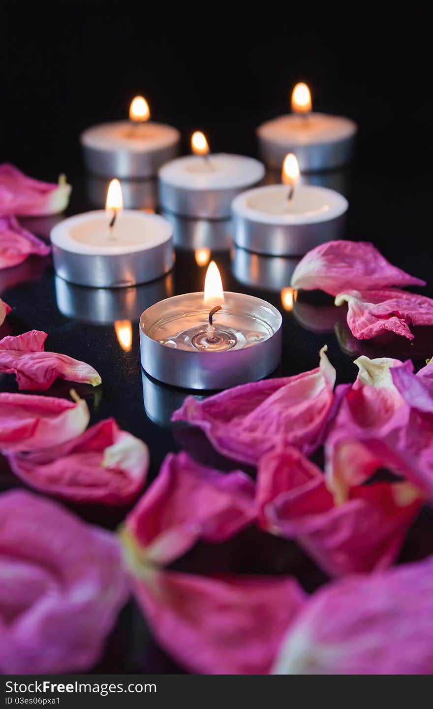 Candles and petals on black background