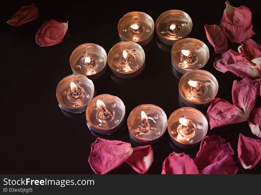 Candles and petals on black background