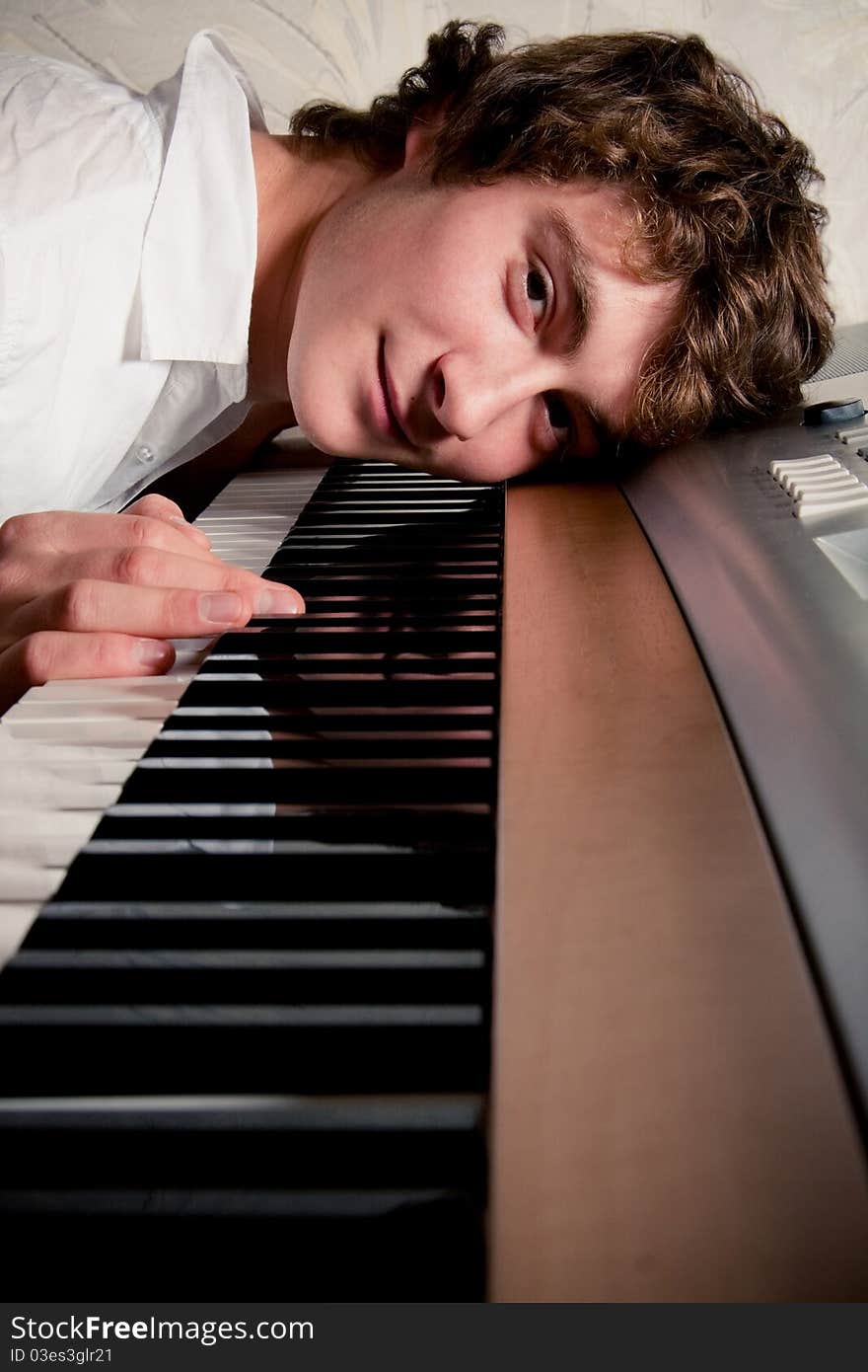 Portrait of a boy lying on a piano keyboard