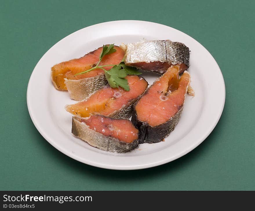 Red raw trout fish on the dish on green background