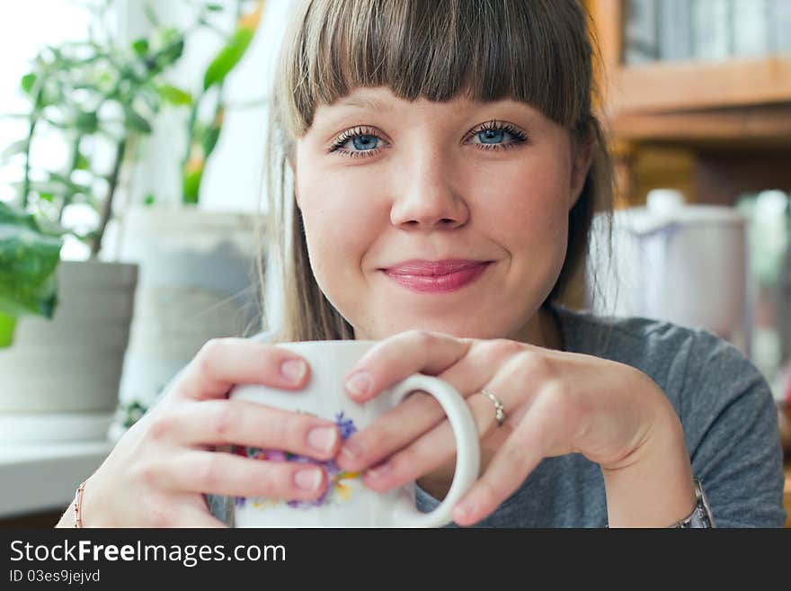 Attractive smiling girl holding a cup of tea indoors. Attractive smiling girl holding a cup of tea indoors