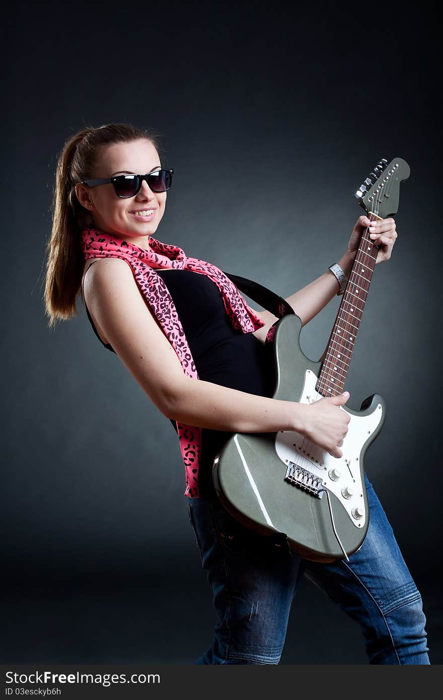 Girl wearing leather jacket with a guitar