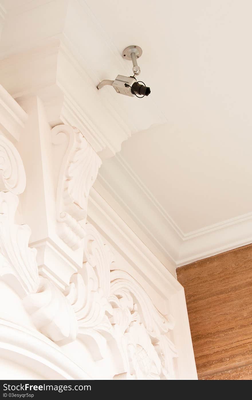 A security surveillance camera installed on a carved ceiling