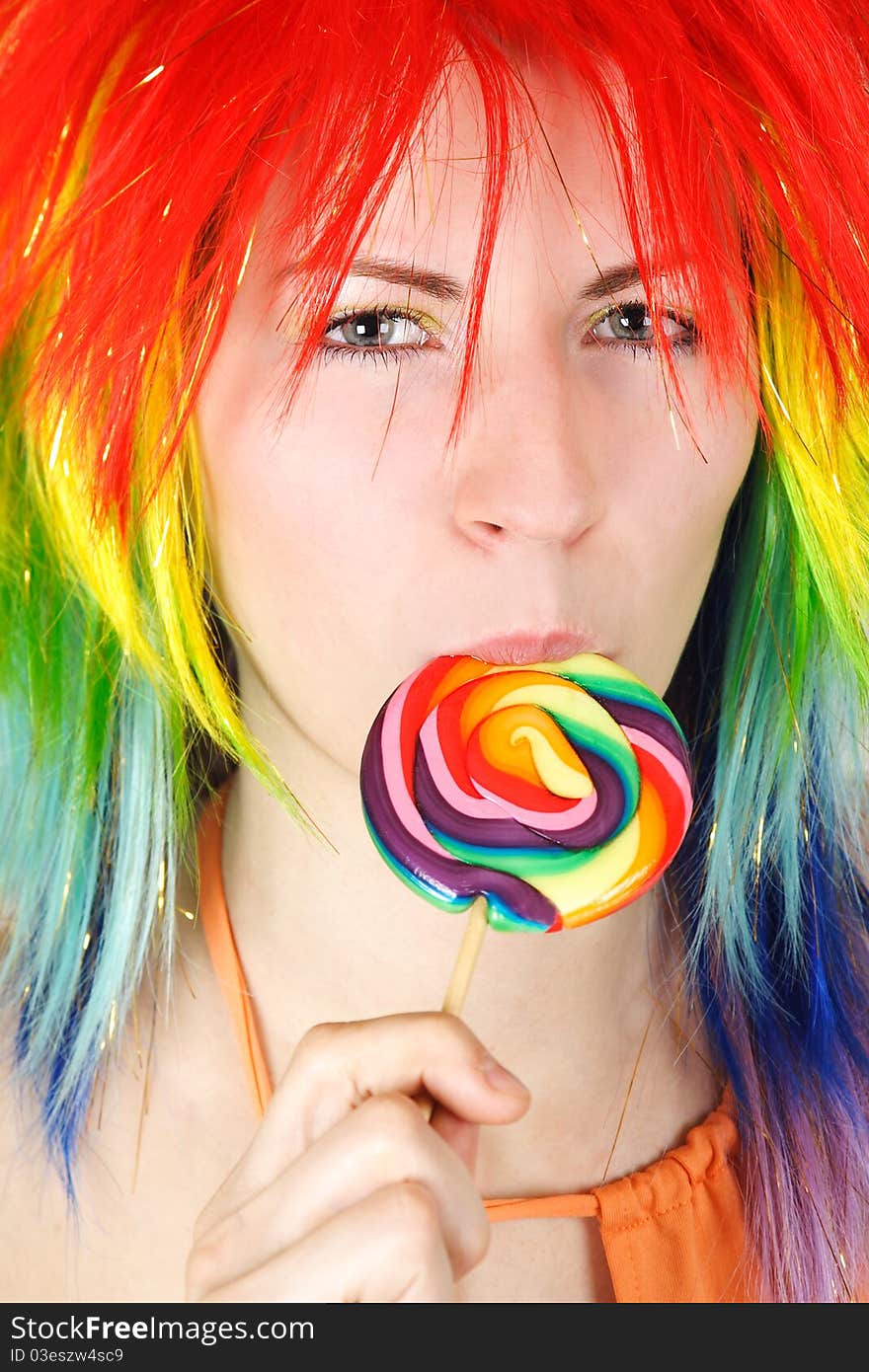 Closeup of young beauty woman in multicolored wig eating big lollipop