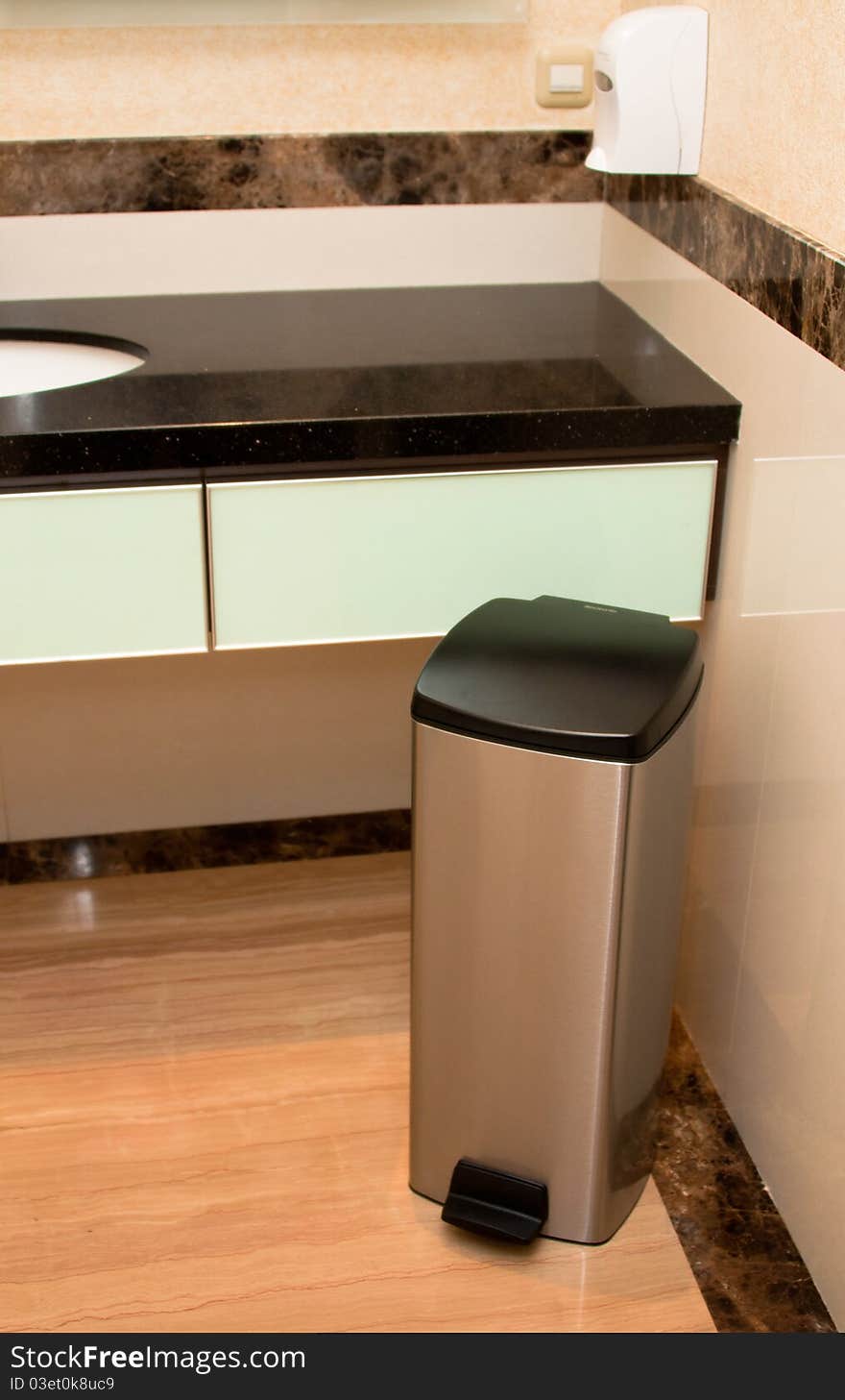 A stainless steel bin inside the luxurious marble washroom. A stainless steel bin inside the luxurious marble washroom