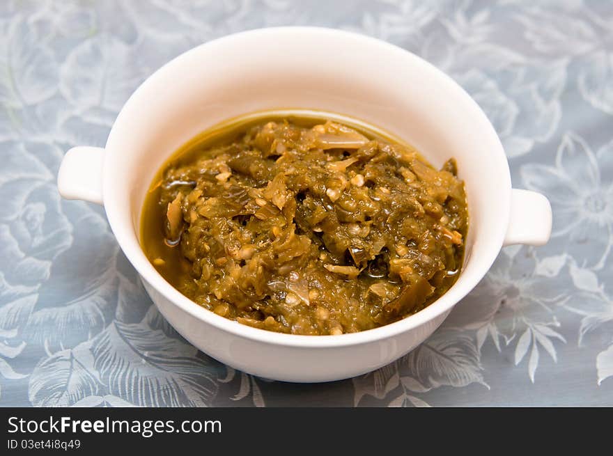 A pounded spicy green chili paste on a white bowl. A pounded spicy green chili paste on a white bowl