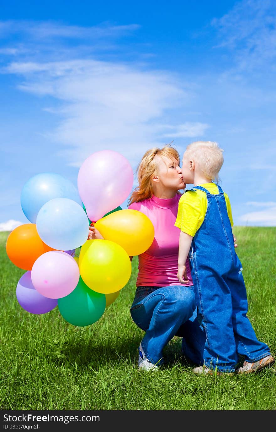 Happy mother and son with balloons outdoor on a summer day