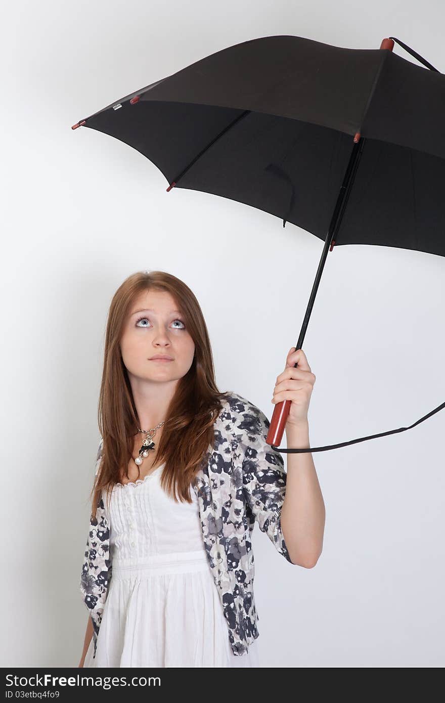 The girl holds the big umbrella and looks upwards. The girl holds the big umbrella and looks upwards