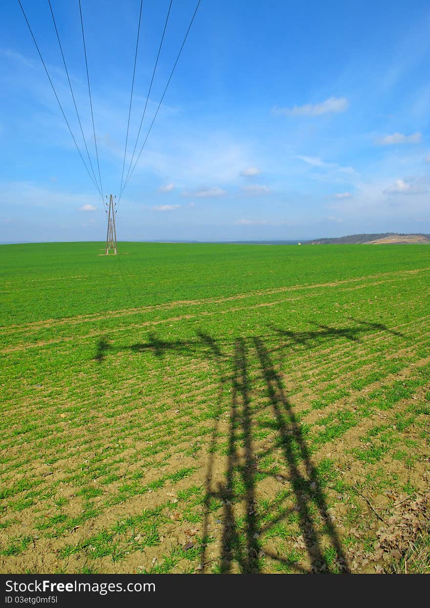 Electric power lines on green field.