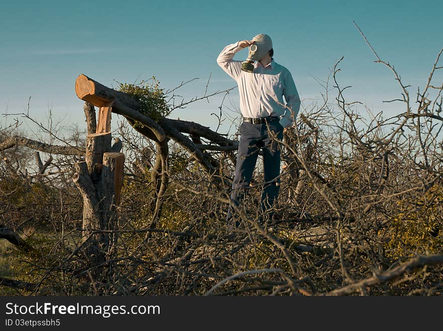 A Man In The Gas Mask Surrounded By Broken Trees.