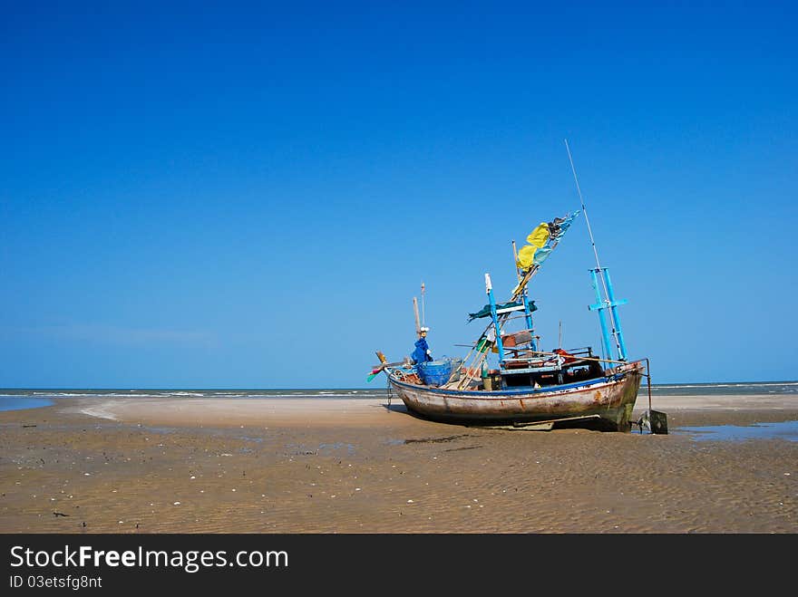 Fisherman boat on the sea shore , with bright blue sky background