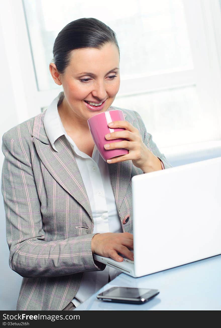 Smiling Young Business Woman With Cup Using Laptop