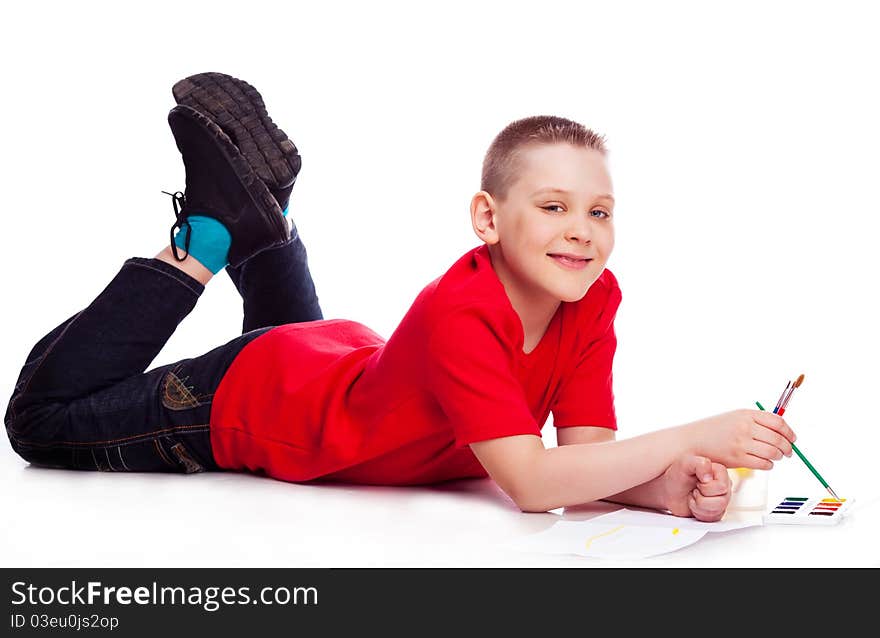 Cute ten year old boy painting with watercolor, isolated against white