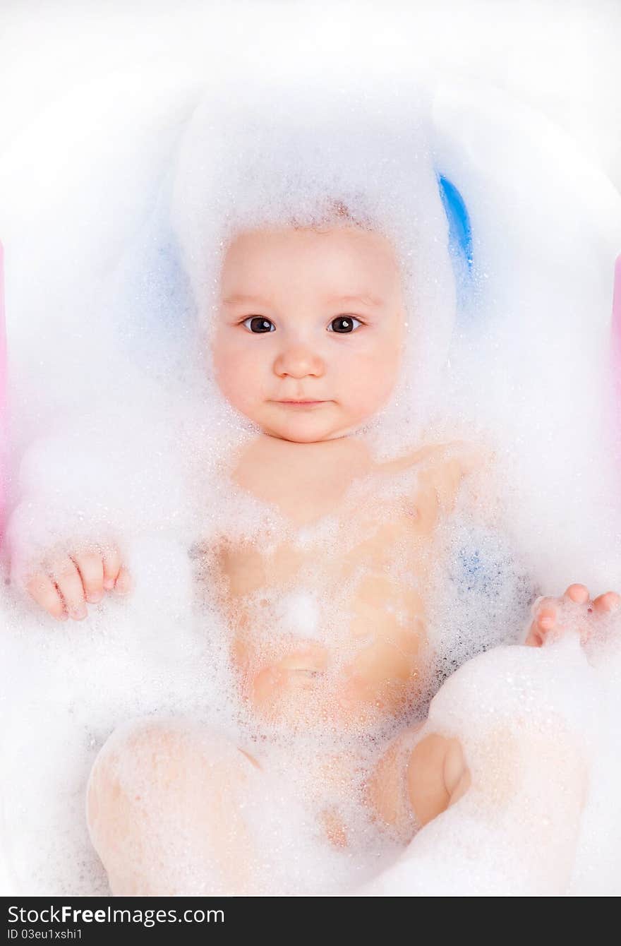 Cute six months old baby taking a relaxing bath with foam. Cute six months old baby taking a relaxing bath with foam