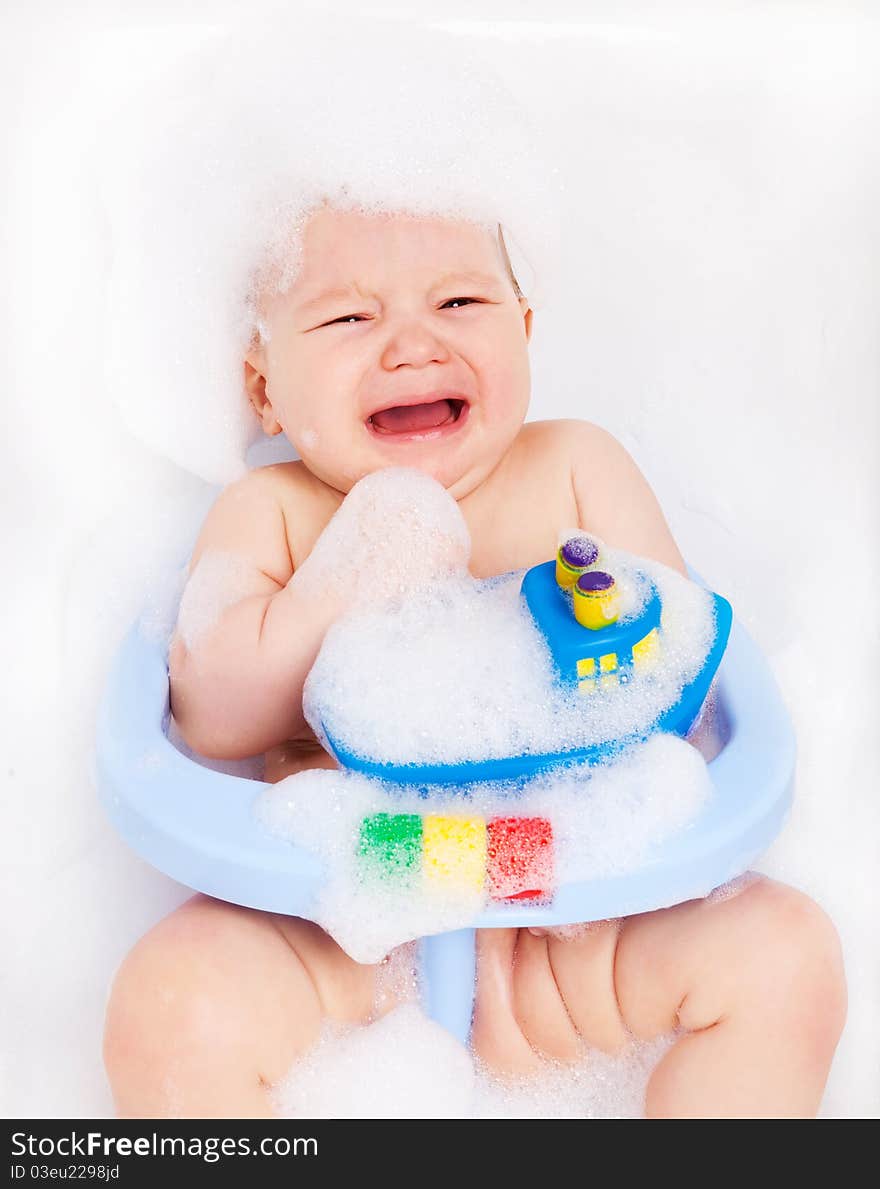 Displeased six months old baby sitting in the baby bath chair. Displeased six months old baby sitting in the baby bath chair