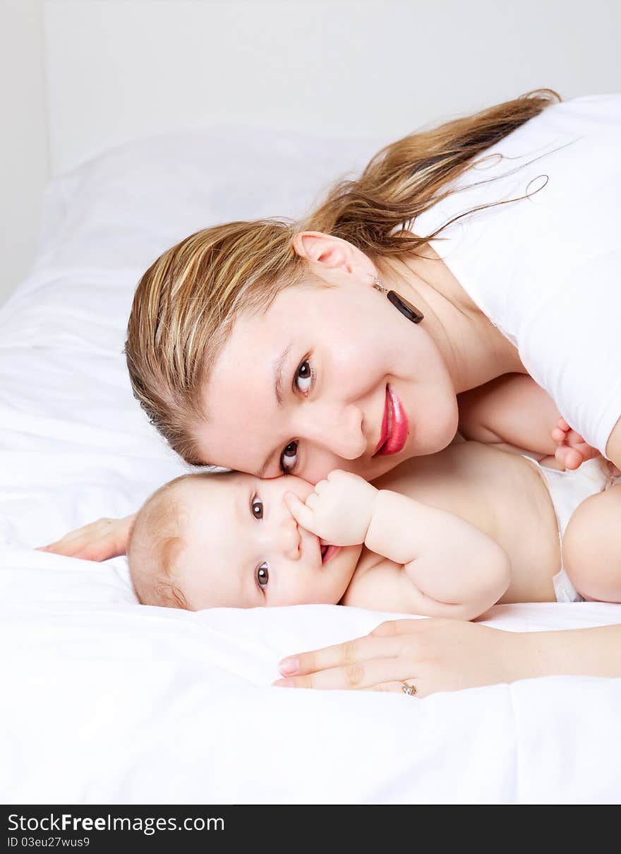 Young mother and her six months old baby on the bed at home. Young mother and her six months old baby on the bed at home