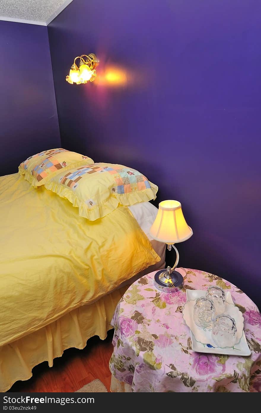 Side table with lighted lamp beside hotel bed. Side table with lighted lamp beside hotel bed.