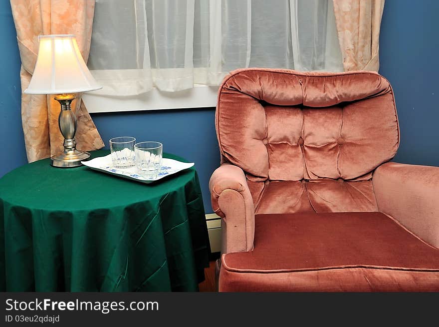 Drinking glasses on side table beside comfortable armchair. Drinking glasses on side table beside comfortable armchair.