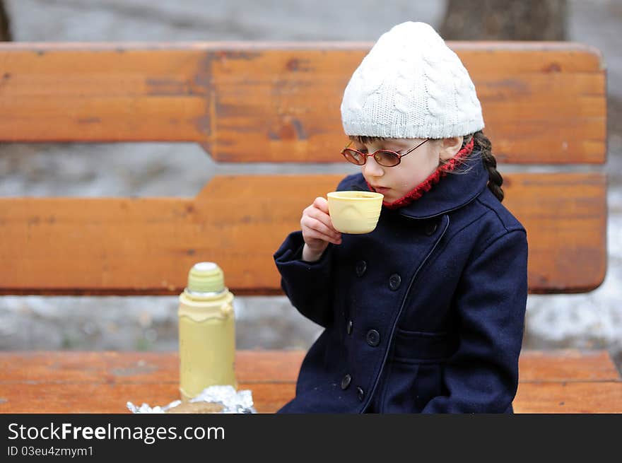 Little girl in white hat eats her lunch in the spring park. Little girl in white hat eats her lunch in the spring park