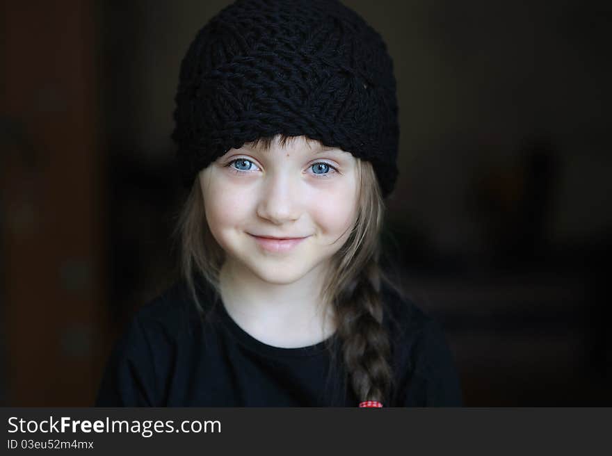 Portrait of cute little girl in black hat on dark background