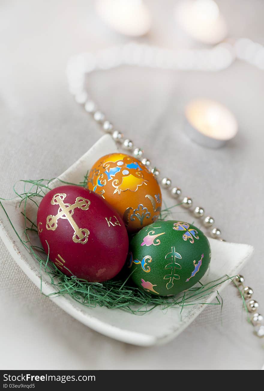 Three colored Easter eggs with decoration and candles