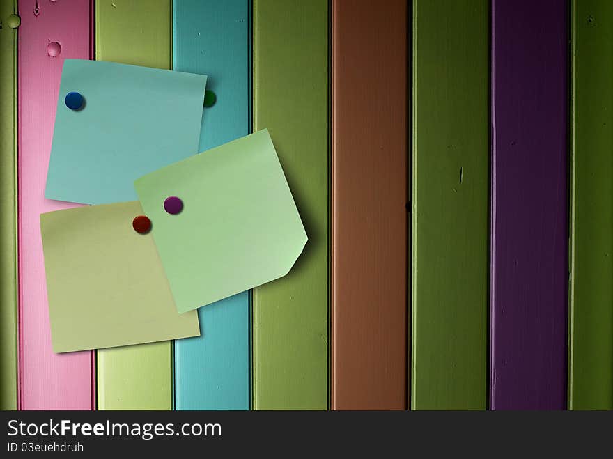 Memo notes over a colorful wooden wall fitted with thumbtack. Memo notes over a colorful wooden wall fitted with thumbtack