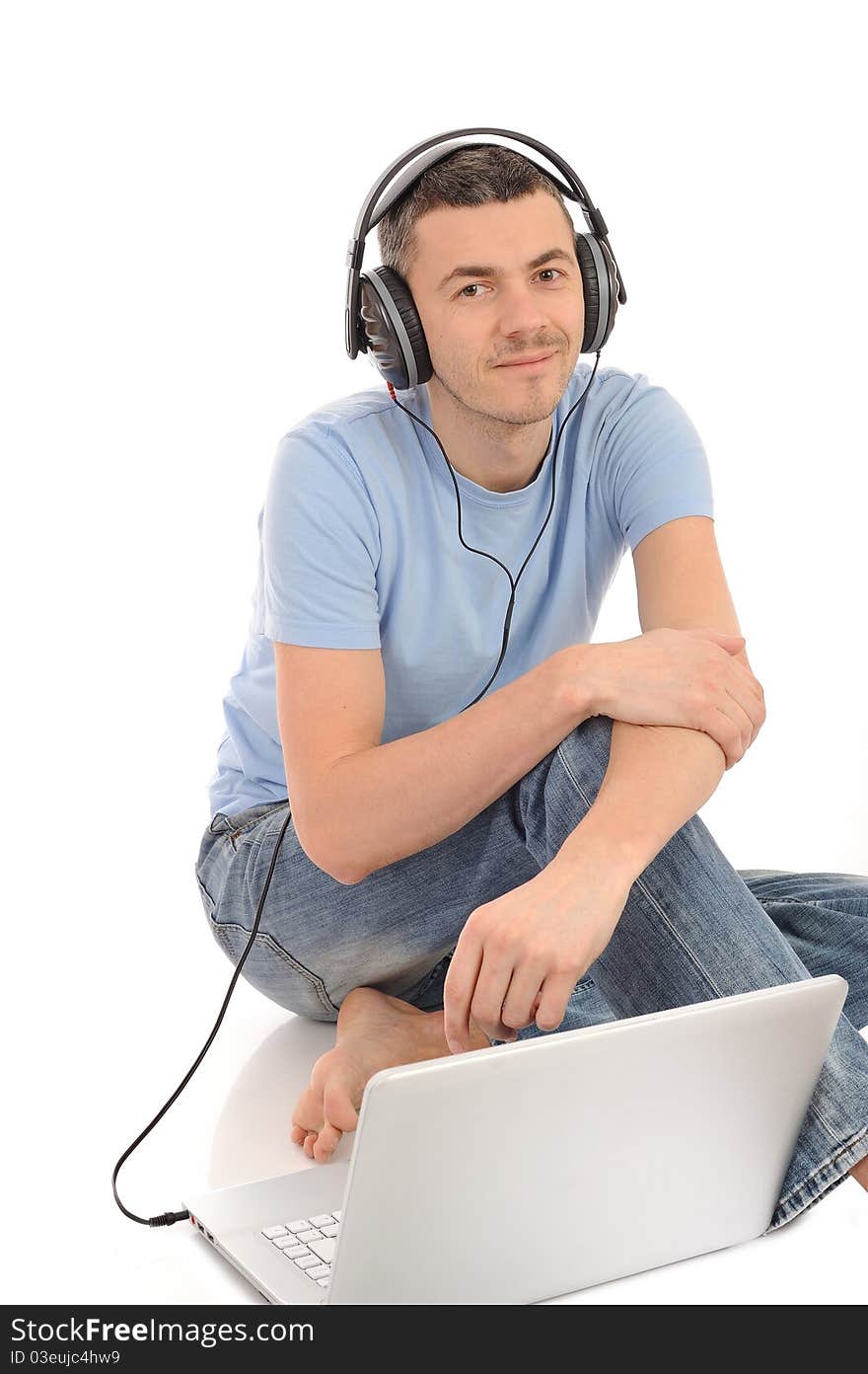 Young handsome man listening to music in headphones from computer. isolated. Young handsome man listening to music in headphones from computer. isolated