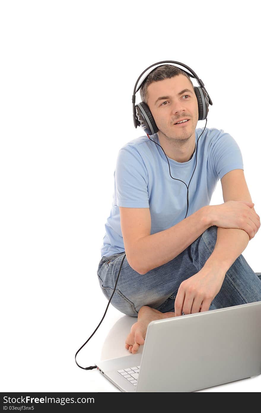 Young handsome man listening to music in headphones from computer. isolated. Young handsome man listening to music in headphones from computer. isolated