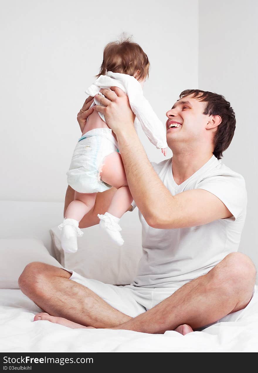 Young father with his six months old daughter on the bed at home. Young father with his six months old daughter on the bed at home