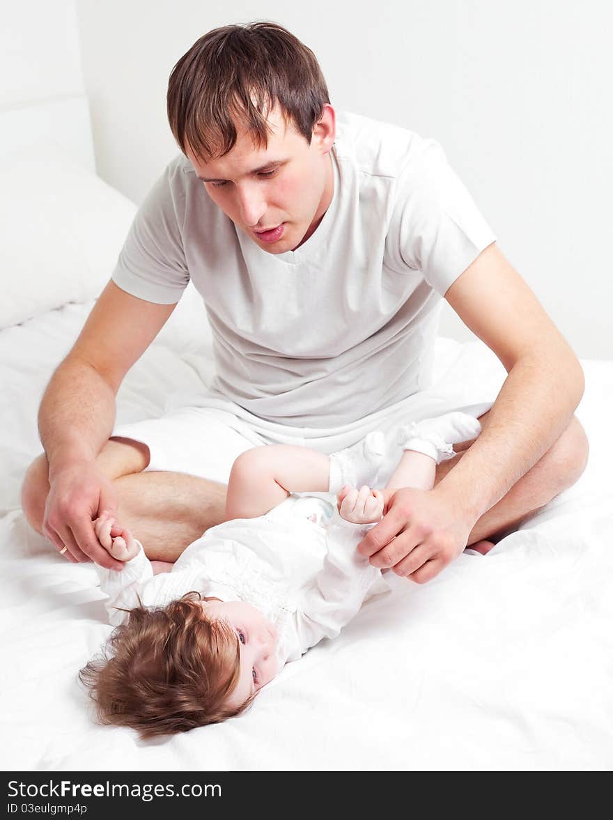 Young father with his six months old daughter on the bed at home. Young father with his six months old daughter on the bed at home