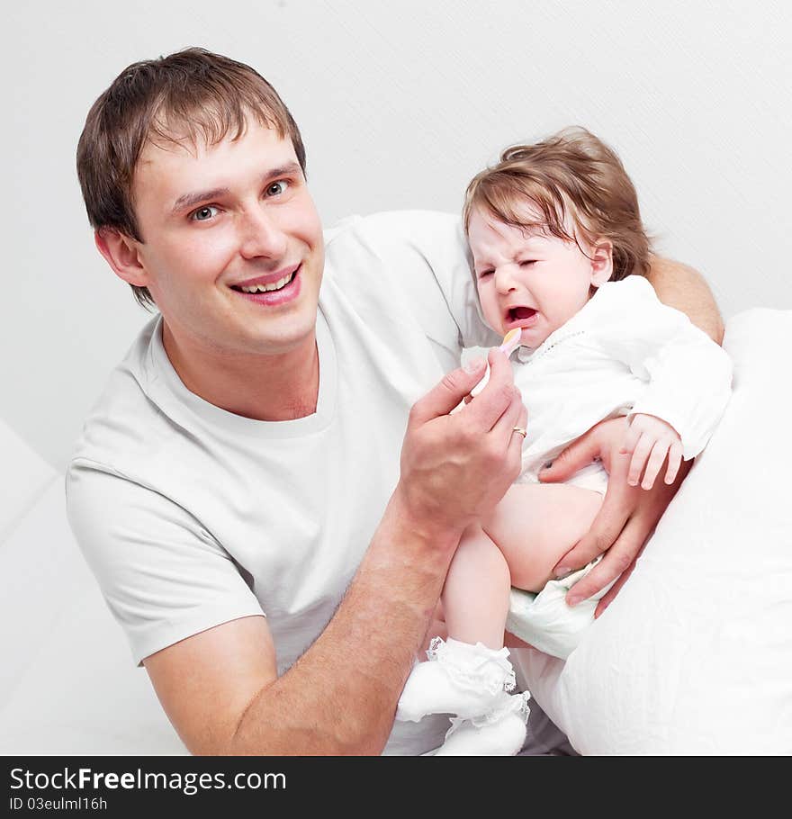 Young father feeding his his six months old daughter on the bed at home. Young father feeding his his six months old daughter on the bed at home