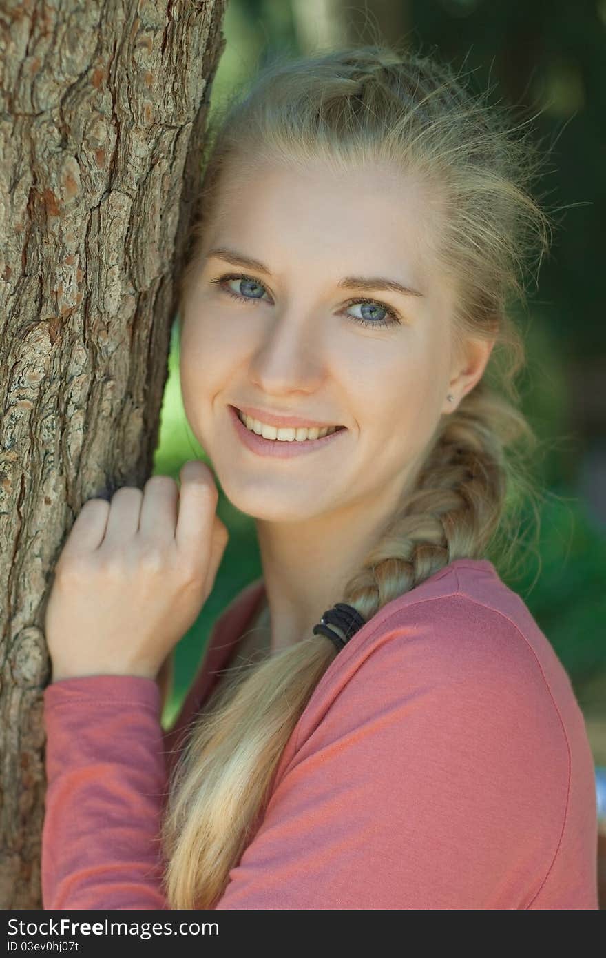 Portrait of a young girl in a park with a romantic smile with blond hair, braided in a braid. Portrait of a young girl in a park with a romantic smile with blond hair, braided in a braid