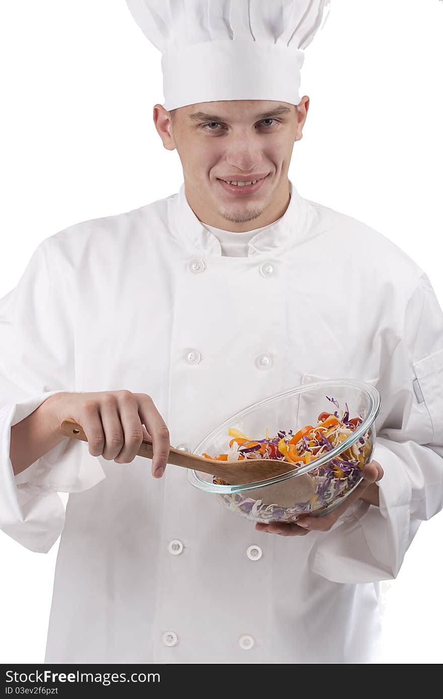 The young chef in uniform and chef's hat in the bowl of salad mixes.