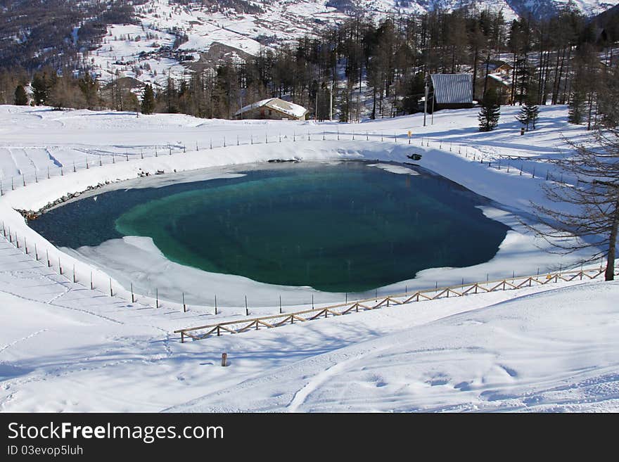 Beautiful artificial lake in the mountain in winter near village. Beautiful artificial lake in the mountain in winter near village