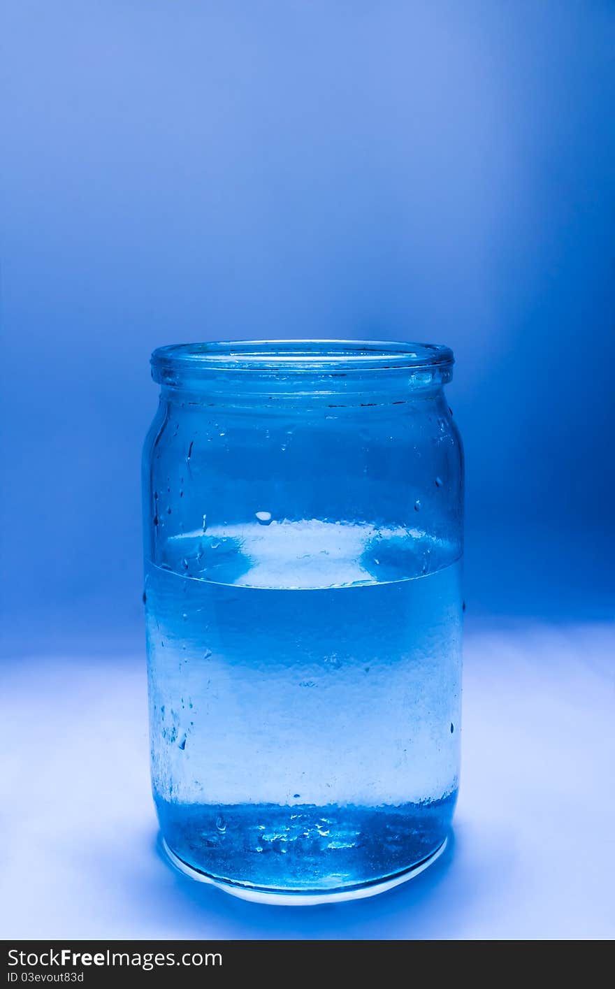 Glass jar filled with water on a blue background. Glass jar filled with water on a blue background