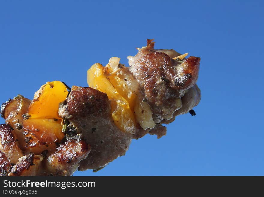 Shish Kebab on the blue sky with yellow pepper and spices