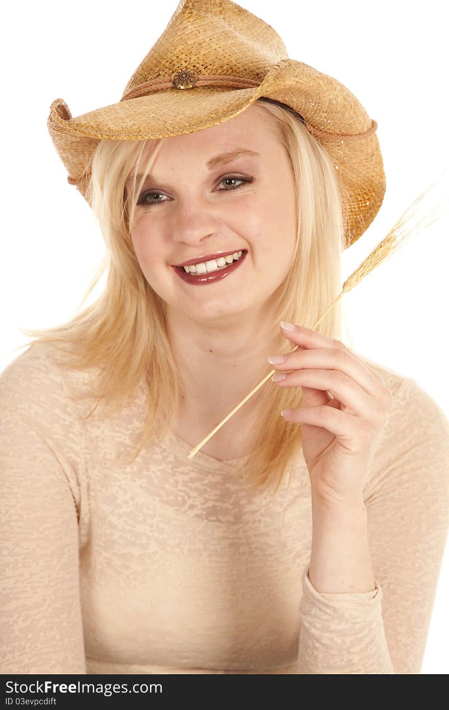 A cowgirl laughing while she holds onto a piece of wheat. A cowgirl laughing while she holds onto a piece of wheat.