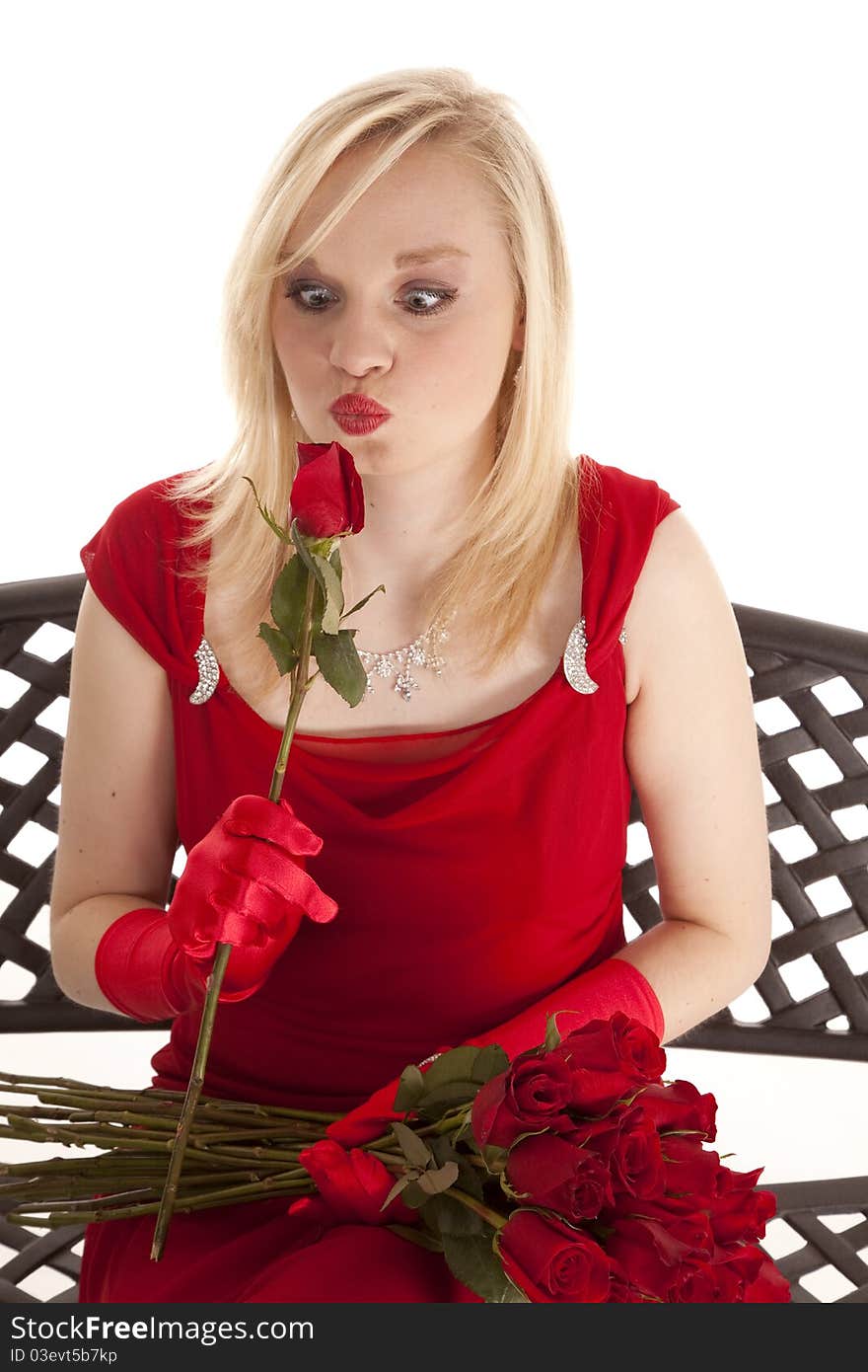 A beautiful teen sitting in her red dress on a metal bench, looking cross eyed at a single rose. A beautiful teen sitting in her red dress on a metal bench, looking cross eyed at a single rose.