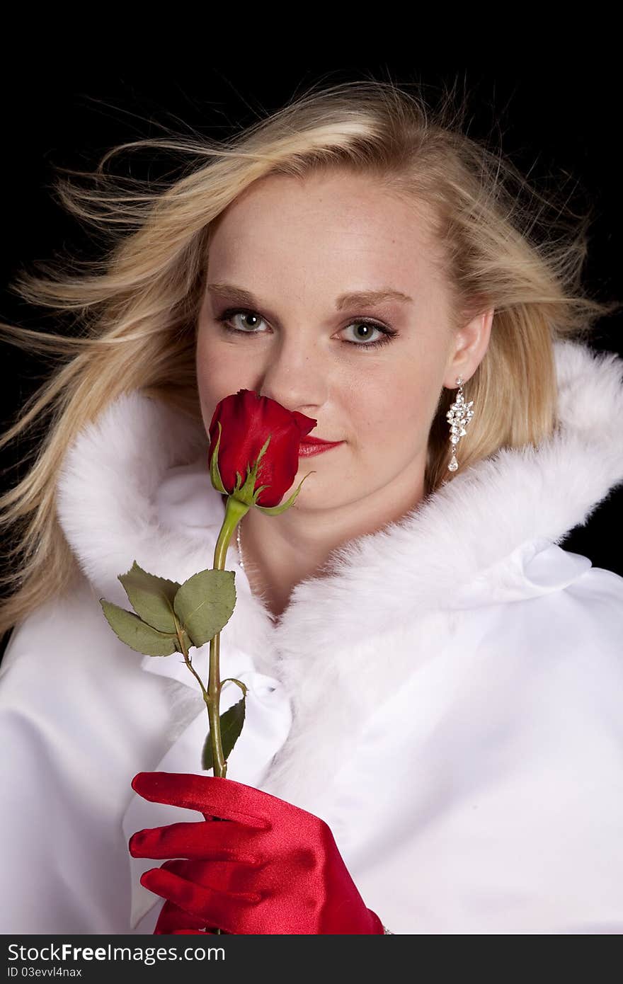 A beautiful teen in her beautiful coat smelling a single rose. A beautiful teen in her beautiful coat smelling a single rose.