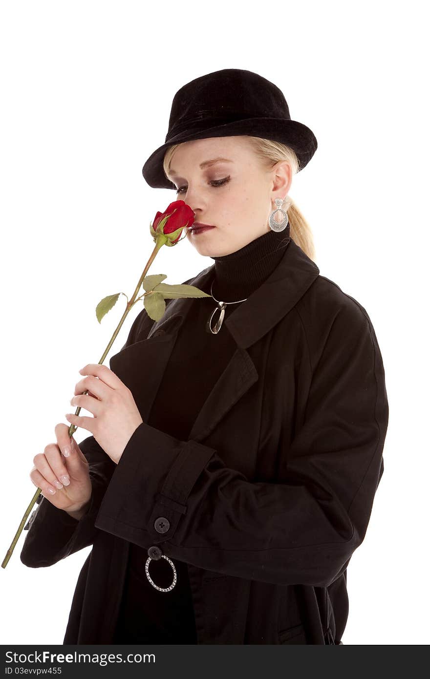 A beautiful girl in a black hat and coat smelling a red rose. A beautiful girl in a black hat and coat smelling a red rose.