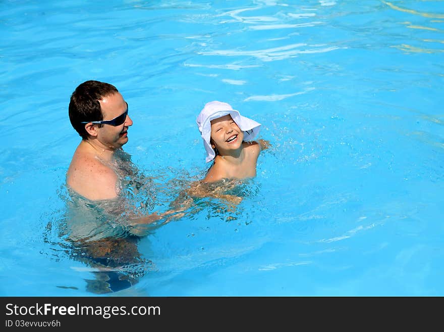 Dad teaches his daughter to swim in the pool. Dad teaches his daughter to swim in the pool