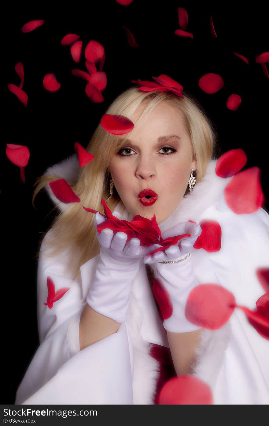 A beautiful teen in her beautiful coat blowing on rose petals towards the camera. A beautiful teen in her beautiful coat blowing on rose petals towards the camera.