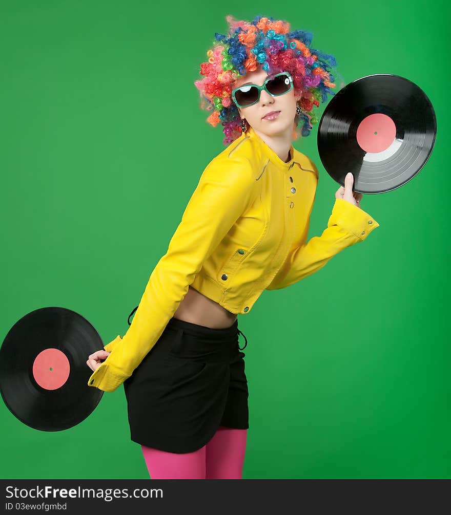 The girl in a color wig with a disk on green background. The girl in a color wig with a disk on green background