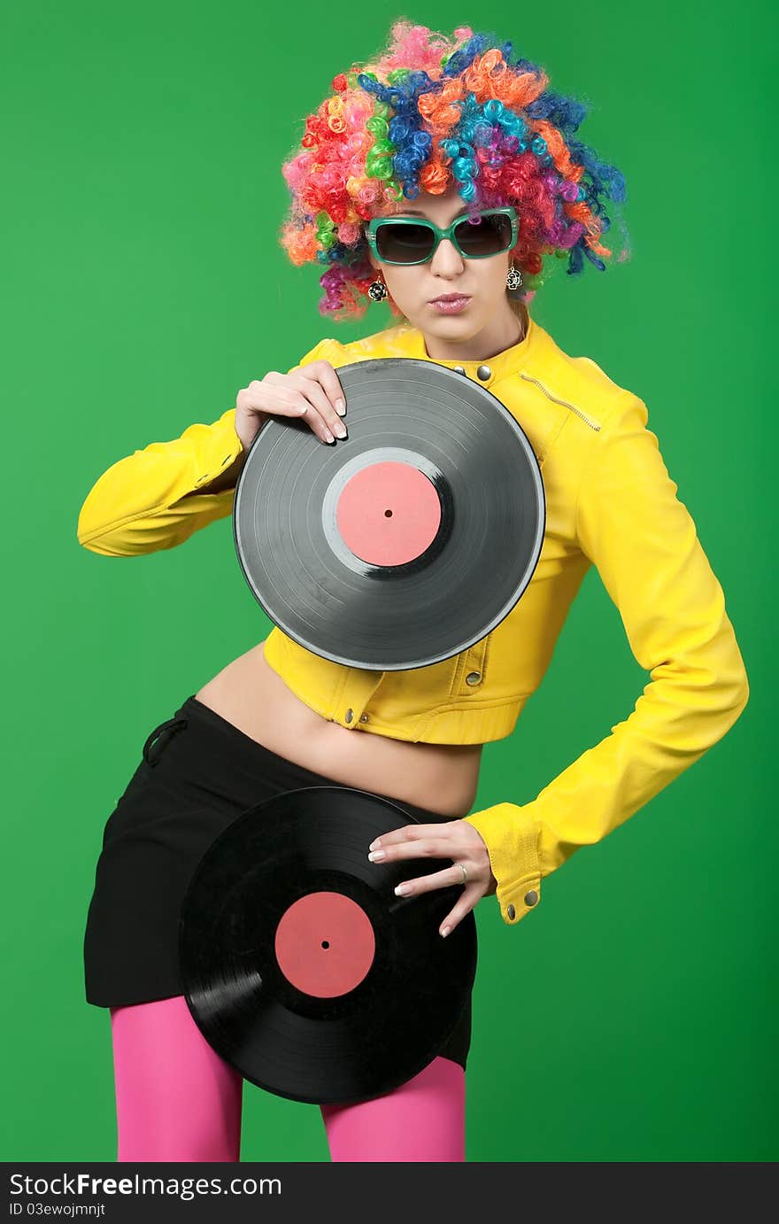 The girl in a color wig with a disk on green background. The girl in a color wig with a disk on green background