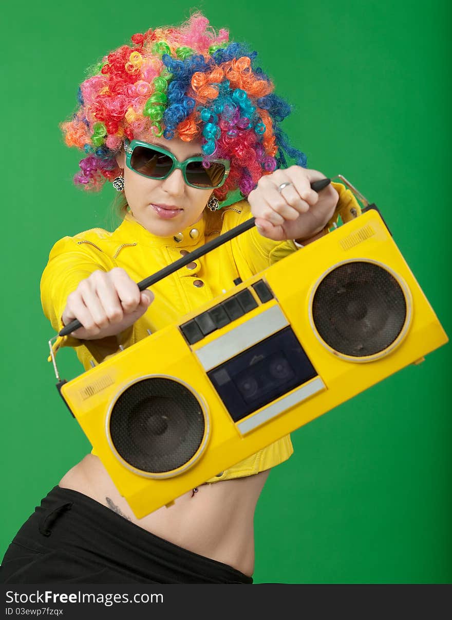 The girl in a color wig with the old tape recorder on green background. The girl in a color wig with the old tape recorder on green background