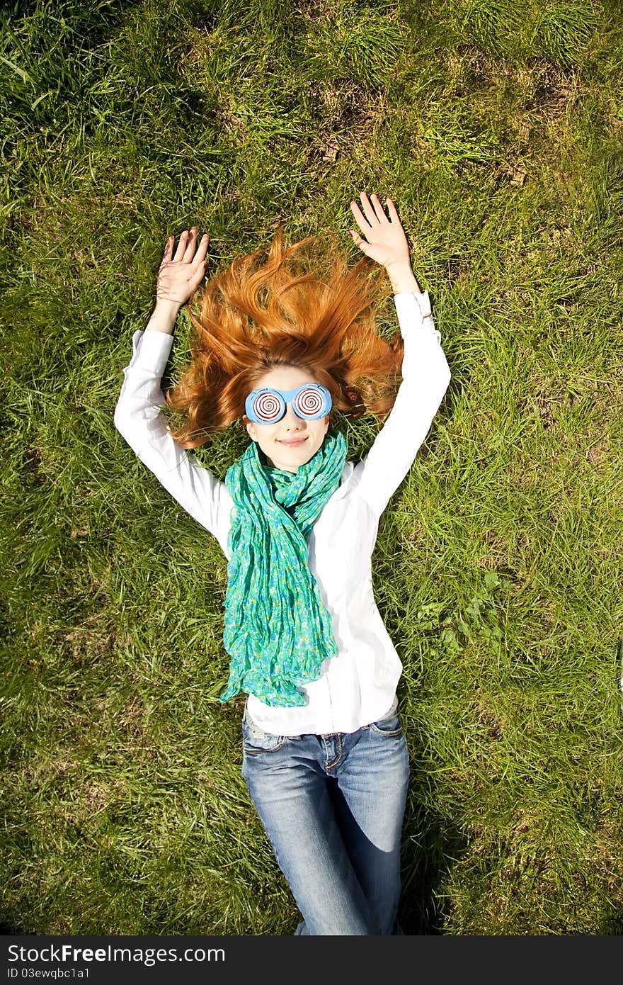 Girl lies at green grass in the park.