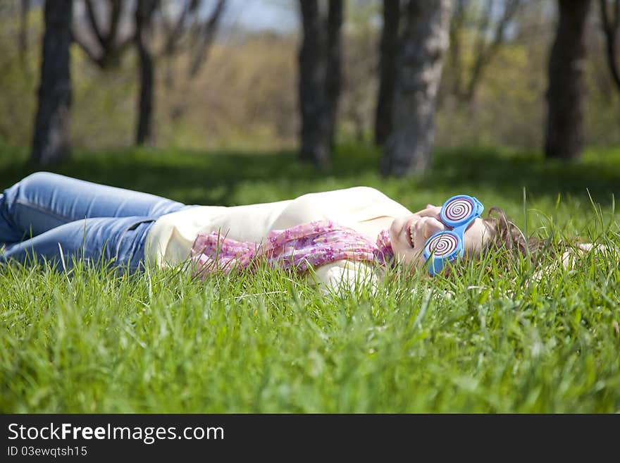 Brunette girl in funny glasses lies at meadow