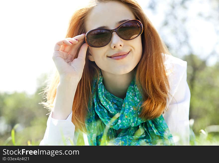 Red-haired girl in sunglasses at the park.