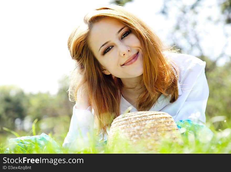 Beautiful red-haired girl with hat at the park.