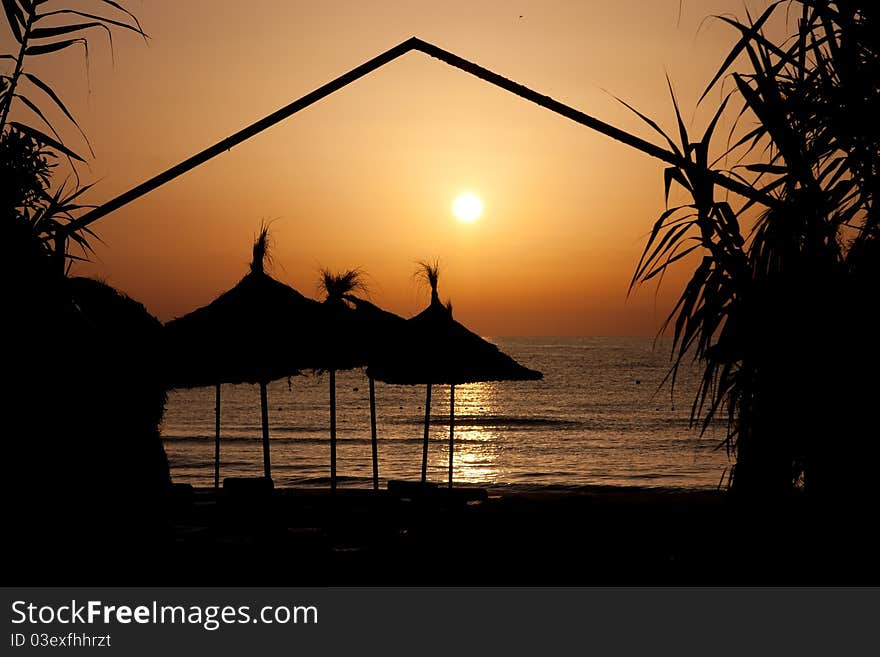 Umbrella silhouette on the beach during the sunrise. Umbrella silhouette on the beach during the sunrise